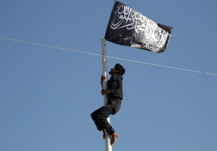 A member of al-Qaida's Nusra Front climbs a pole where a Nusra flag was raised at a central square in the northwestern city of Ariha