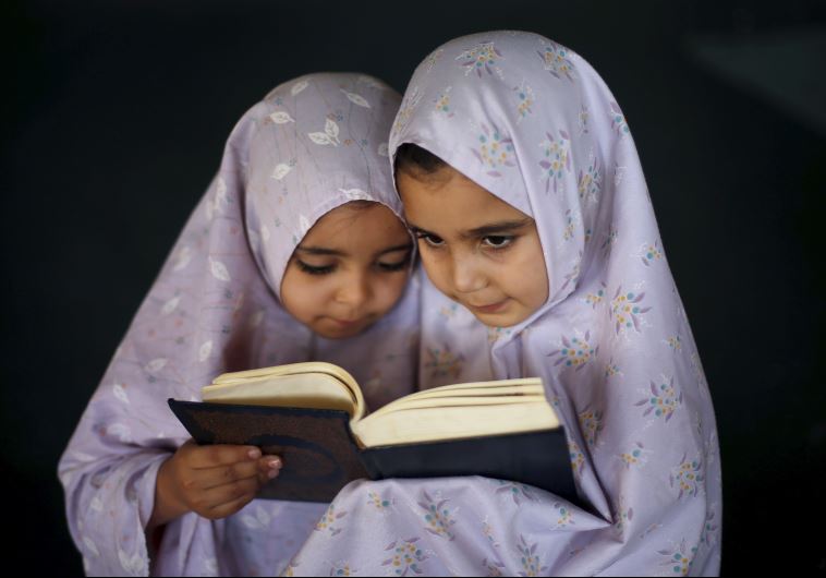 Palestinian girls read the Koran as they attend a Koran memorization lesson during summer vacation inside a mosque in Gaza City