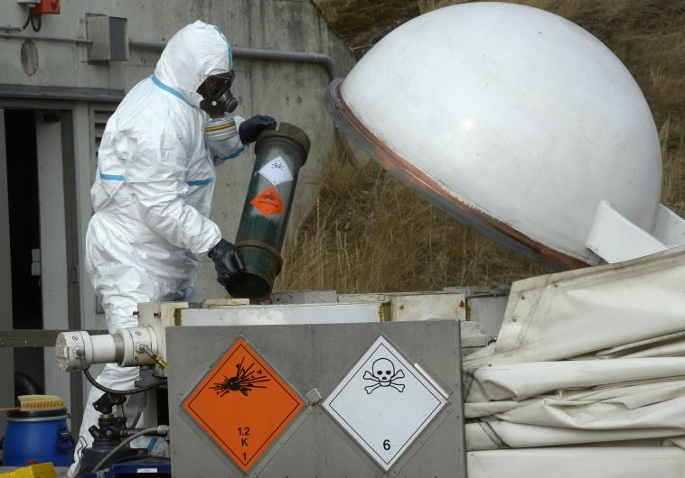 A worker dressed in protective clothing, handles a dummy chemical World War Two weapon.