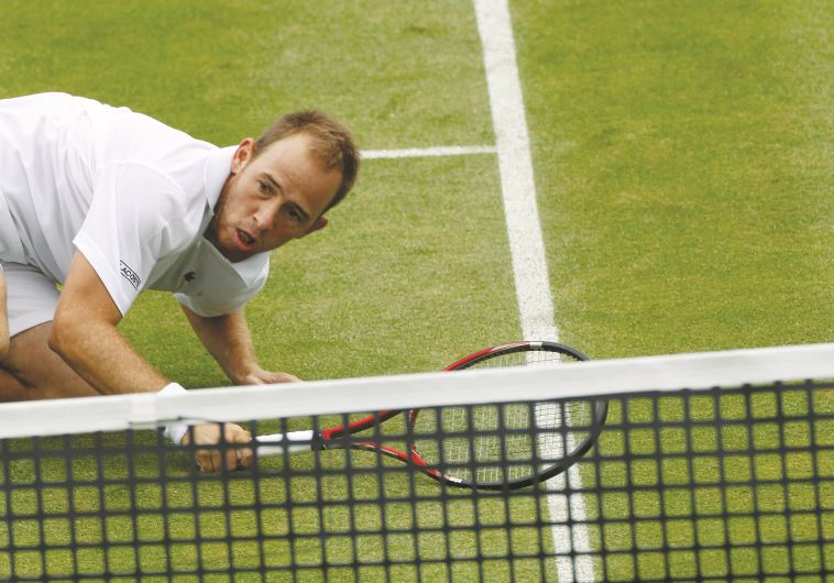 Dudi Sela falls to the grass during his first-round loss at Wimbledon