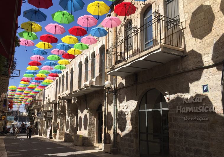 People walk under colourful umbrellas decorating a pedestrian mall in downtown Jerusalem June 30, 2015.