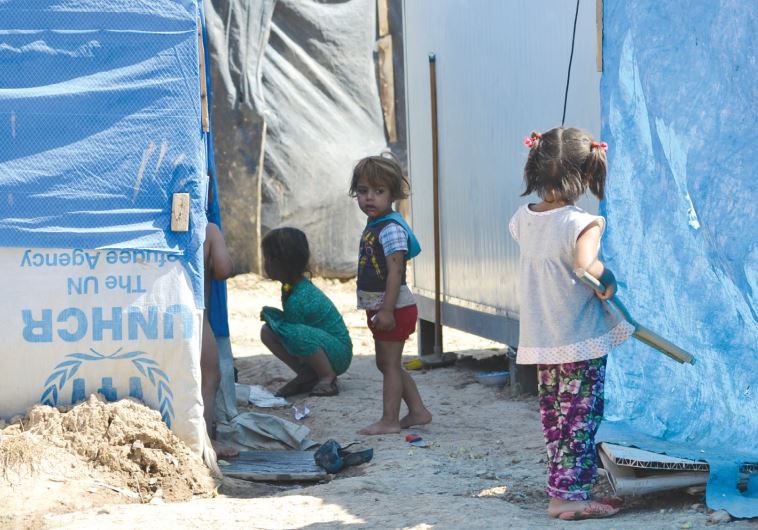 Children play outside their temporary shelters at the Harsham refugee camp.