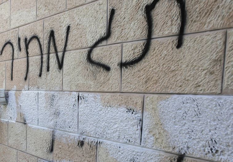 A municipal worker paints over ‘price tag’ graffiti daubed in Hebrew on a wall of the Romanian Orthodox Church in Jerusalem, May 9, 2014.