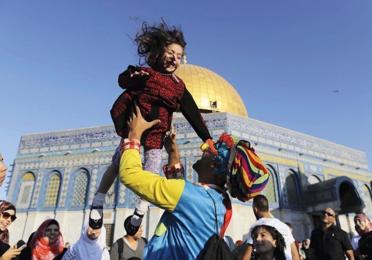 A MAN DRESSED as a clown plays with a girl on Friday, Id al-Fitr, near the Dome of the Rock on Jerusalem’s Temple Mount