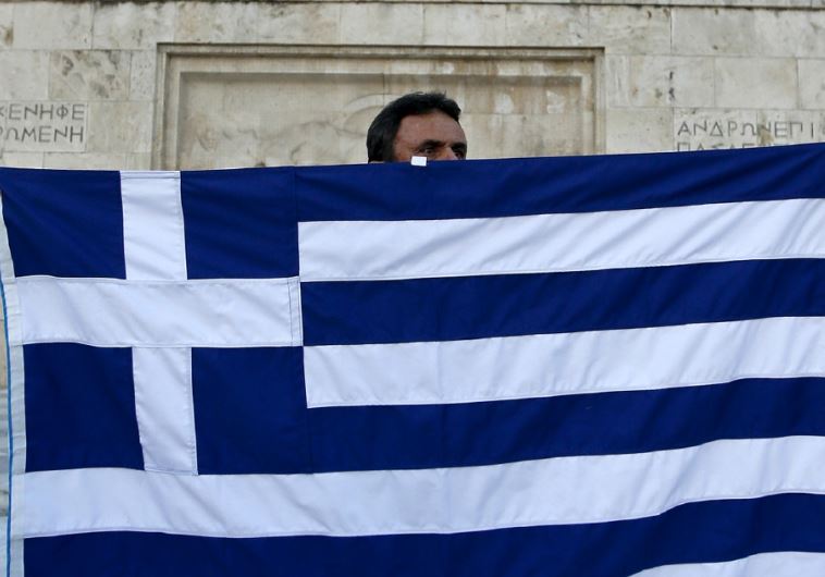 An anti-EU protester unfurls a Greek national flag on the Tomb of the Uknown Soldier in front of the parliament in Athens, July 13.