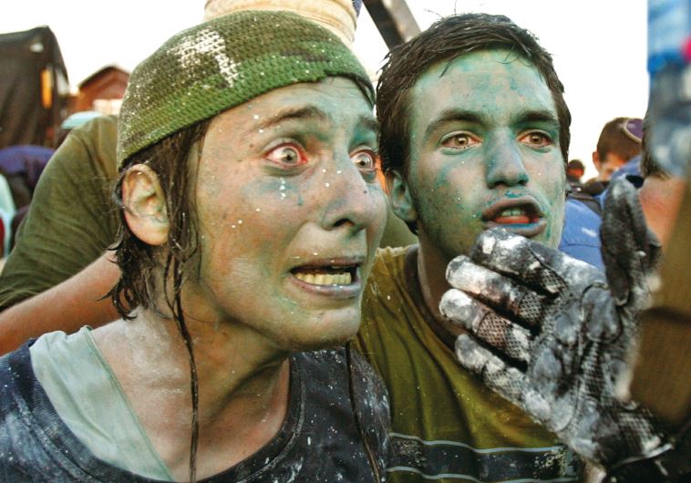 Residents in Gush Katif argue with a policeman after being sprayed with colored water cannon on August 18, 2005.