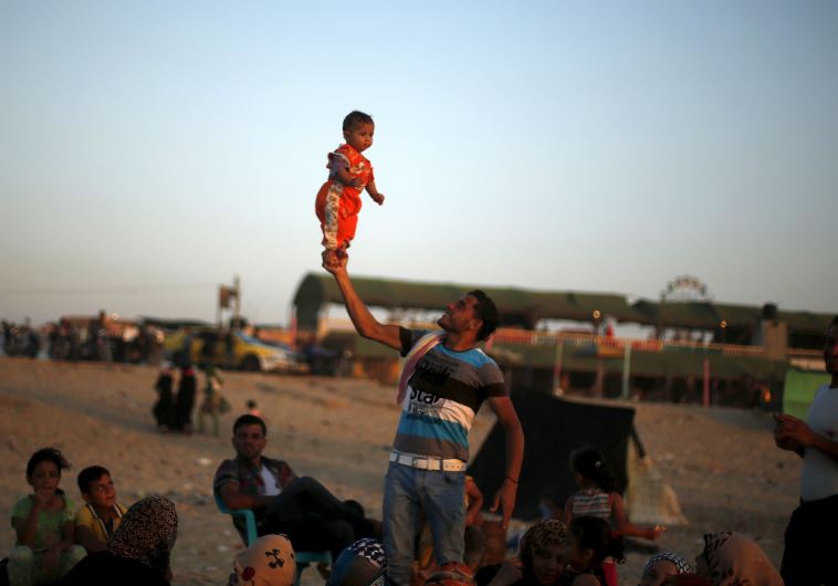 A Palestinian man lifts his daughter at beach along the Mediterranean Sea in the northern Gaza Strip July 24, 2015. 