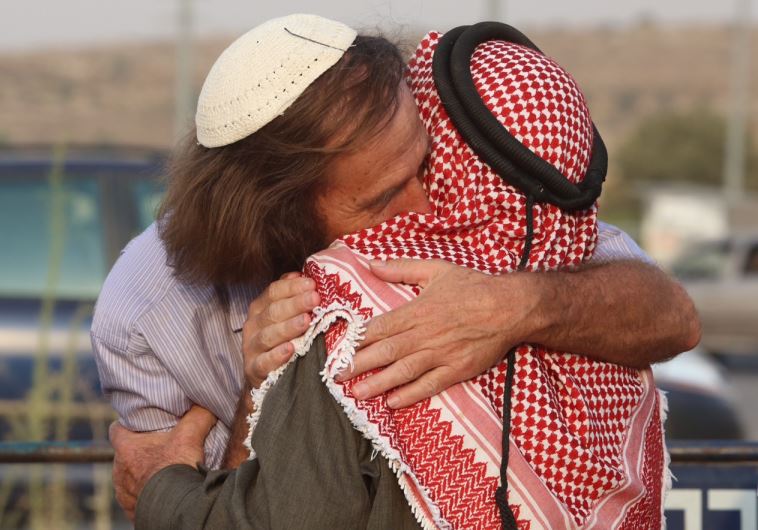 A rabbi and a sheikh embrace at a co-existence meeting