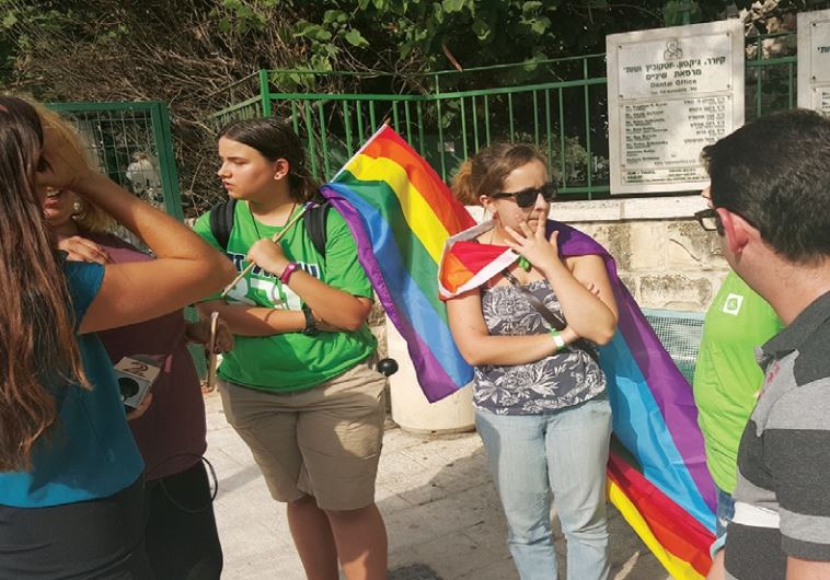 Noam Eyal (right), a stabbing victim, and others revisit the site of last week’s pride parade attack, near the corner of the capital’s Keren Hayesod and Washington streets.