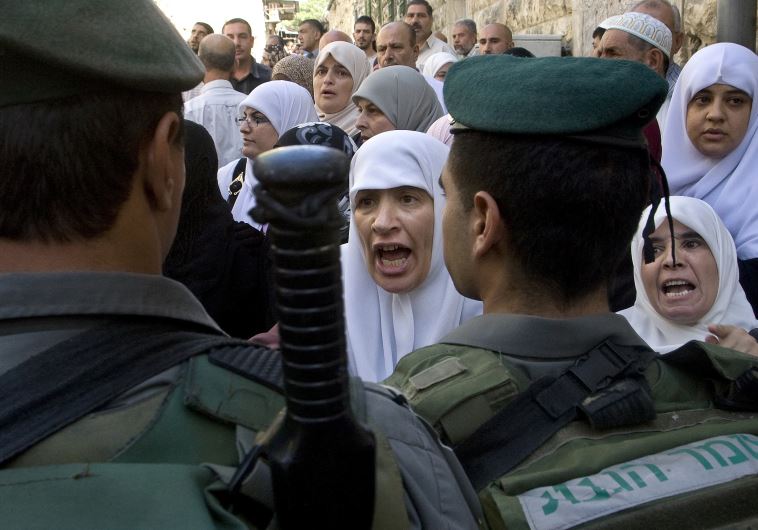 Palestinian women shout in front of Israeli border police officers 