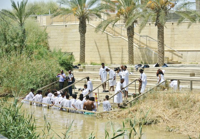 African pilgrims immerse themselves on the Israeli side of the Jordan River. Inset, a view of the Jordanian baptism site on the other side of the river.