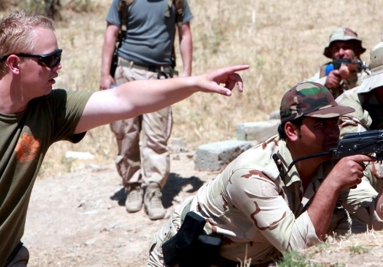 An officer from the Western coalition forces gives advice to Kurdish Peshmerga forces during a training session on how to defend the front lines against ISIS in Daquq district, northern Iraq, June 15