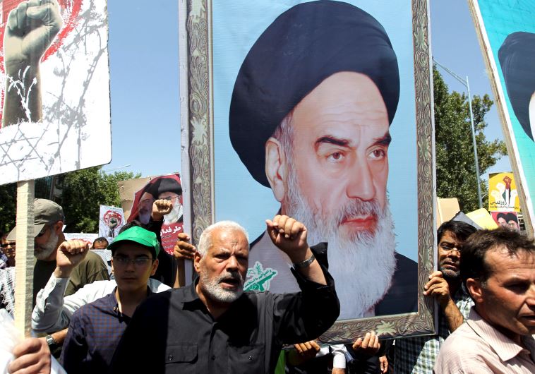 Demonstrators shout slogans in front of a poster depicting Iran's late leader Ayatollah Khomeini during a rally in Tehran