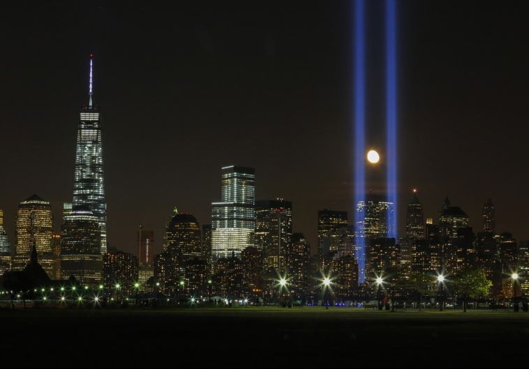 The moon rises between the "Tribute in Light" illuminated next to One World Trade Center