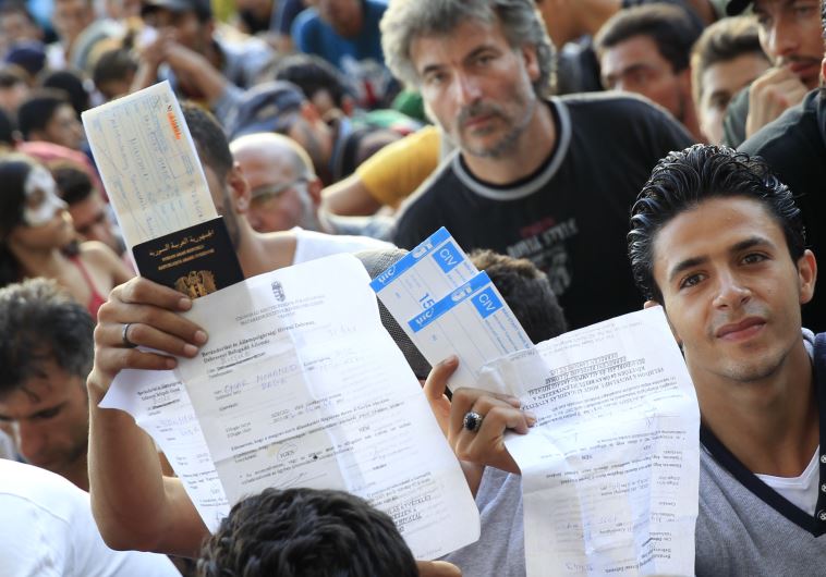 Refugees raise their documents and railways tickets outside the Keleti station in Budapest, Hungary 
