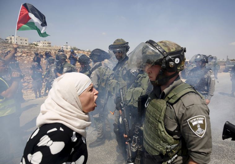 A Palestinian woman argues with an Israeli border policeman during a protest against Jewish settlements in the West Bank village of Nabi Saleh