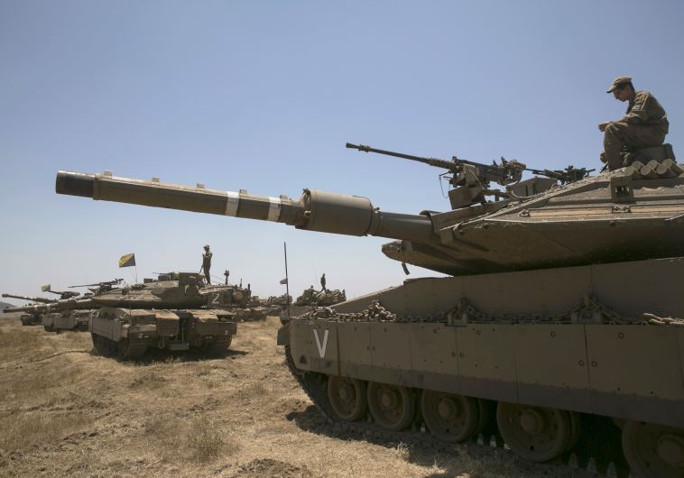 An Israeli soldier sits atop a tank during an exercise in the Golan Heights, near the ceasefire line between Israel and Syria