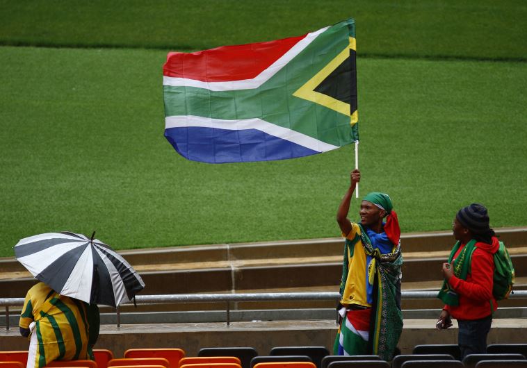 A man raises the South African national flag during the service for former South African President Nelson Mandela at the First National Bank Stadium