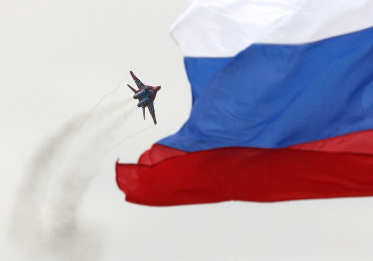 A MiG-29 fighter jet performs a manoeuvre as the Russian national flag flies in the foreground