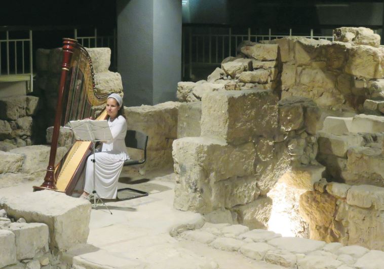 A woman plays the harp among excavations as part of holiday visits