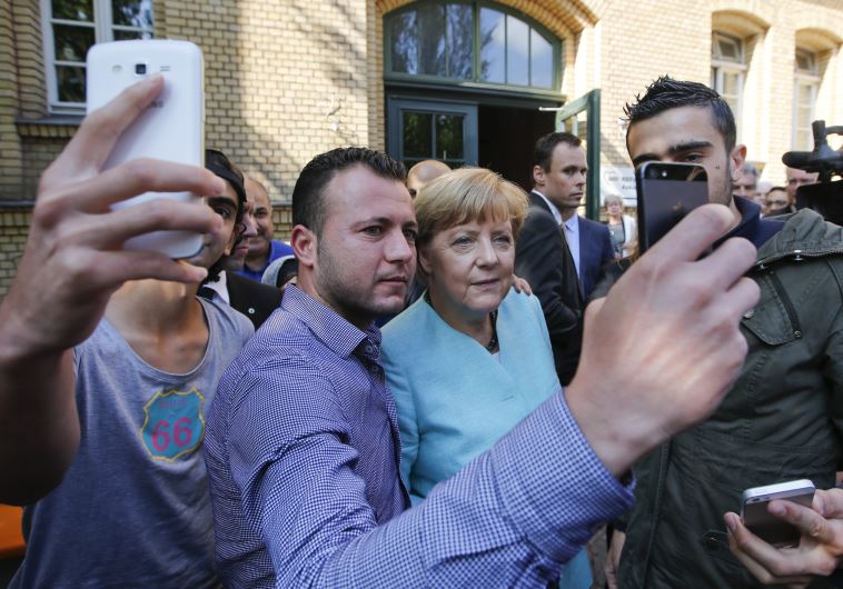 Migrants from Syria and Iraq take selfies with German Chancellor Angela Merkel outside a refugee camp near the Federal Office for Migration and Refugees after their registration at Berlin's Spandau district, Germany, September 10, 2015