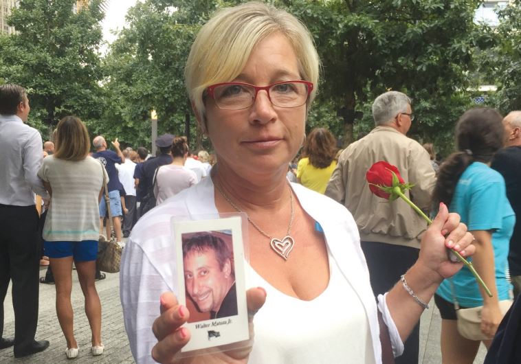 DENISE MATUZA holds her husband’s picture at the memorial on Friday. He died in the North tower 14 years ago