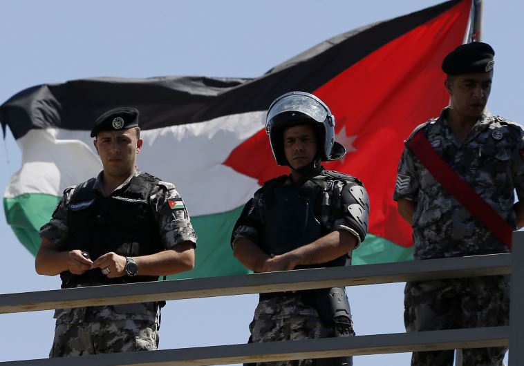 Jordanian riot police stand guard in front of a Jordanian flag as protesters hold a demonstration against Israel in Amman