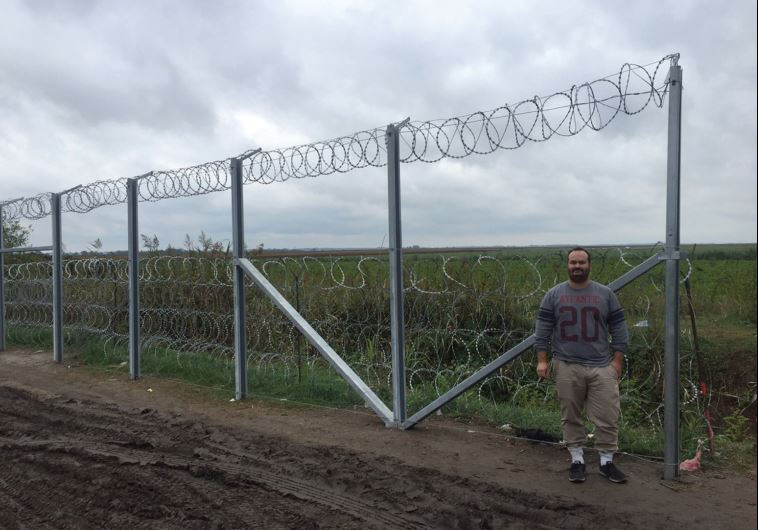 THE WRITER poses next to the fence along the Hungarian border