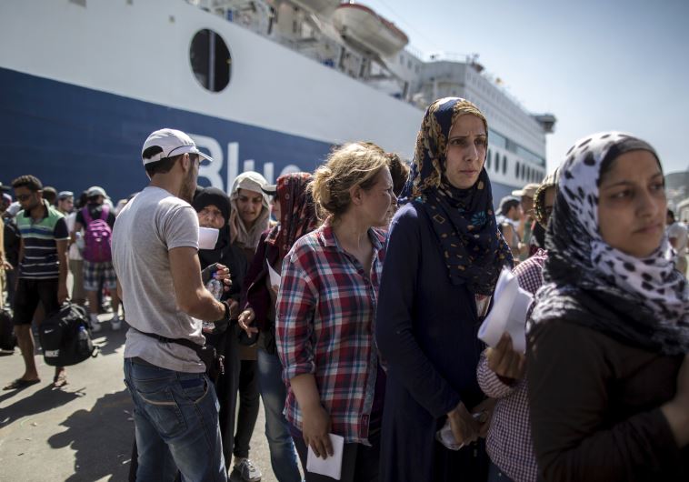 Syrian migrants queue with others to buy a ticket for a ferry trip to Athens from the Greek island of Lesbos 