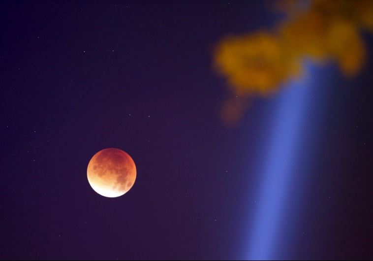 The Moon, appearing in a dim red color, is covered by the Earth's shadow during a total lunar eclipse over Paris