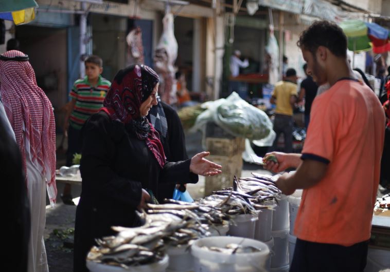A Palestinian woman buys traditional fish eaten during Eid, ahead of the Muslim Eid al-Fitr holiday, at a market in Khan Younis