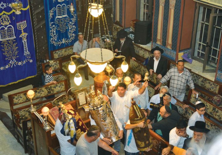 Men dance with Torah scrolls at the Ades Synagogue in Jerusalem