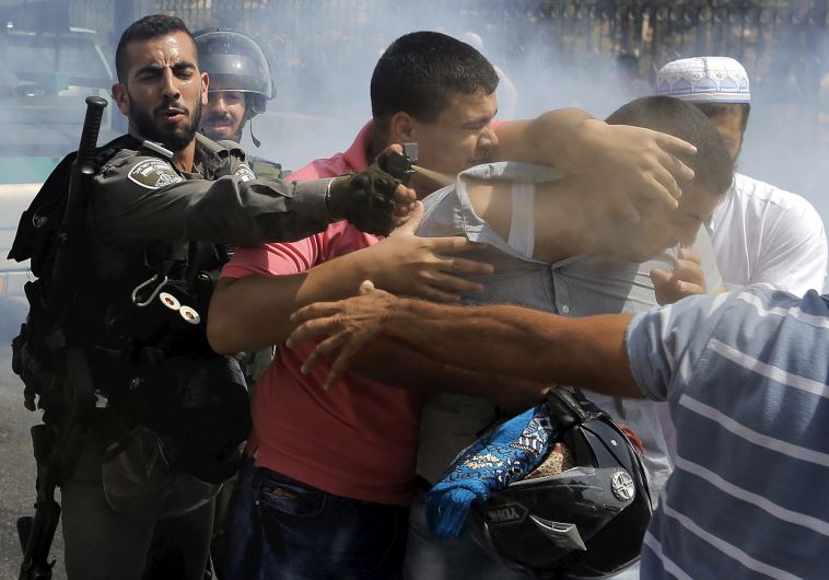 A Border Policeman uses pepper spray on a Palestinian man during clashes near the east Jerusalem neighborhood of Wadi al-Joz