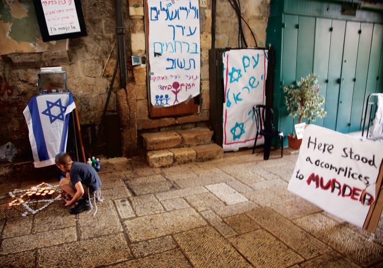A child pays homage at the site in Jerusalem’s Old City where Rabbi Nehemia Lavi and Aharon Banita were stabbed to death on October 3