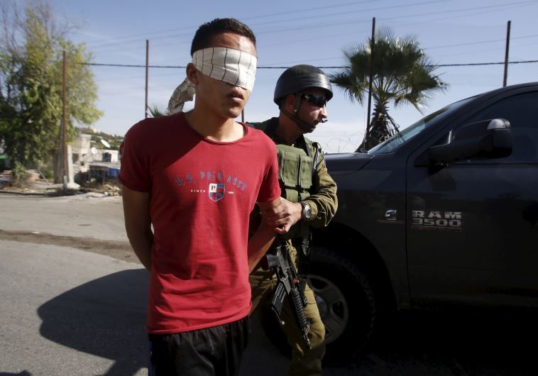 IDF soldier detains a Palestinian during clashes in Beit Ommer village north of the West Bank city of Hebron
