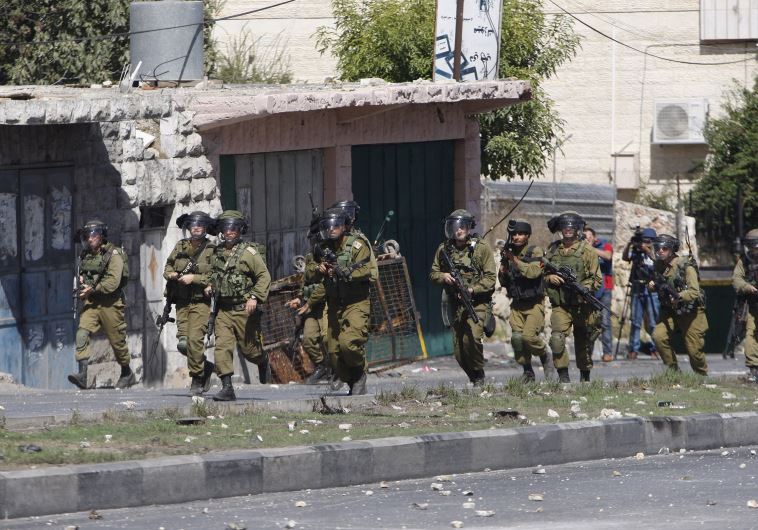 IDF soldiers take up a position during clashes with Palestinian protesters in the West Bank city of Hebron October 13, 2015