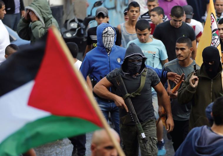 Palestinian gunmen in Shuafat carry weapons during a funeral march for a Palestinian terrorist, shot dead by police after stabbing two Israelis in Jerusalem’s Old City