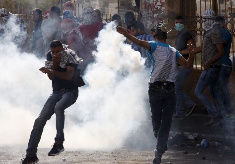 A Palestinian throws back a tear gas canister fired by Israeli troops during clashes in the West Bank city of Bethlehem October 14, 2015