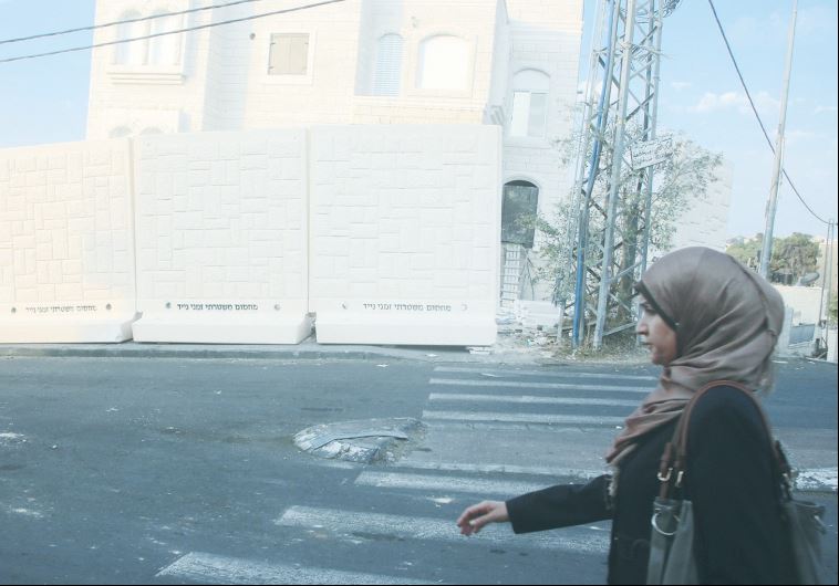 A WOMAN PASSES a section of the uncompleted temporary barrier being erected yesterday to separate the Jerusalem neighborhoods of Armon Hanatziv and Jebl Mukaber.
