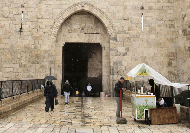 A man buys street food as it rains near Damascus Gate in Jerusalem's Old City