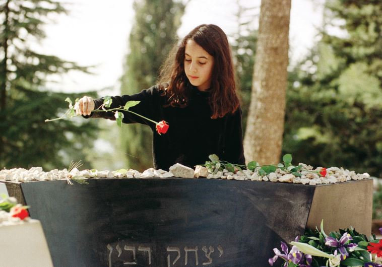 A girl lays a red rose on the grave of slain prime minister Yitzhak Rabin on Jerusalem’s Mount Herzl