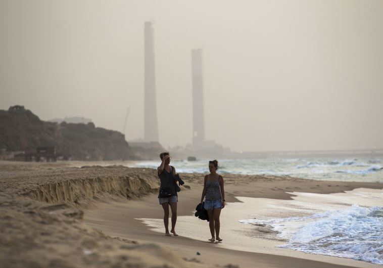 Tourists walk at the shore of the Mediterranean sea in Ashkelon in southern Israel during heavy hazy weather in the region