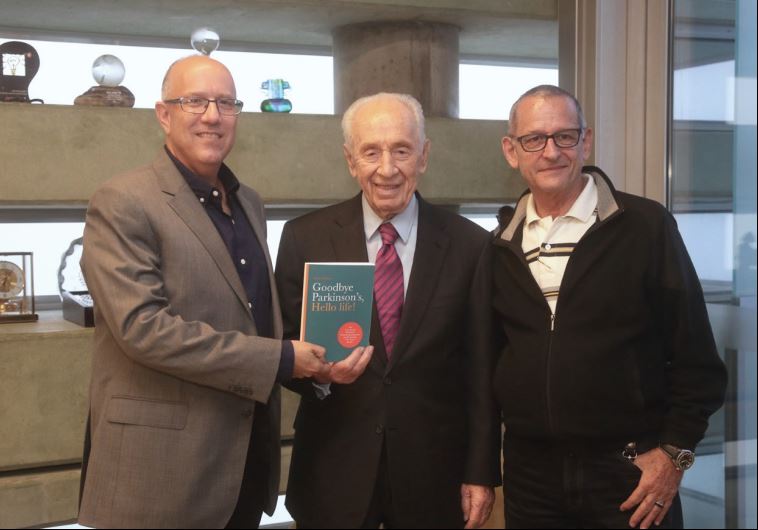 ‘JERUSALEM POST’ Managing Editor David Brinn (left) and Parkinson’s disease therapist Alex Kerten present former president Shimon Peres with a copy of their forthcoming book.