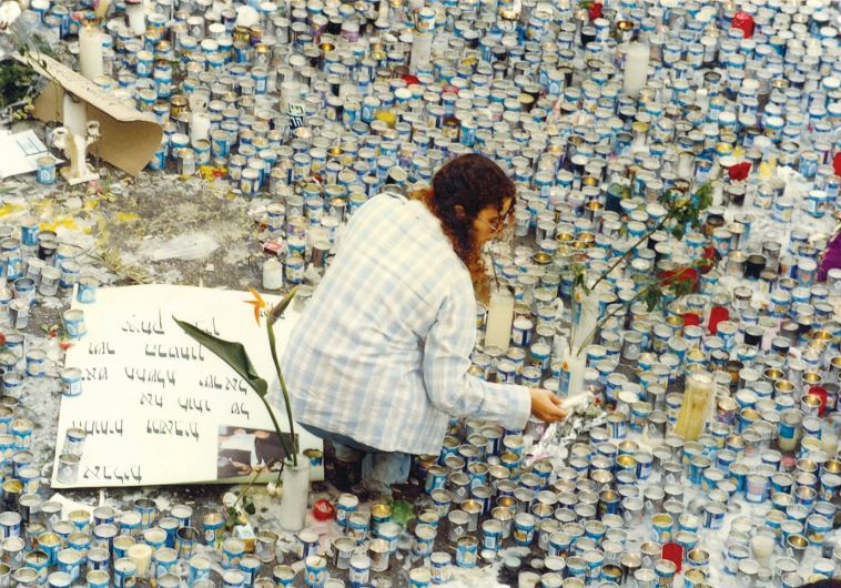A woman lights at candle at a memorial site set up after prime minister Yitzhak Rabin was assassinated in Tel Aviv, in 1995