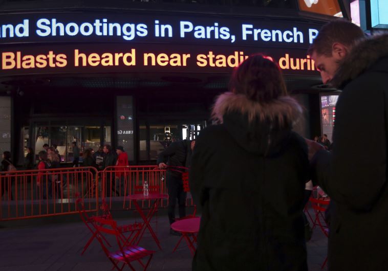 People watch as a news ticker updates people with the news of the shooting attacks in Paris, in Times Square in the Manhattan borough of New York November 13, 2015