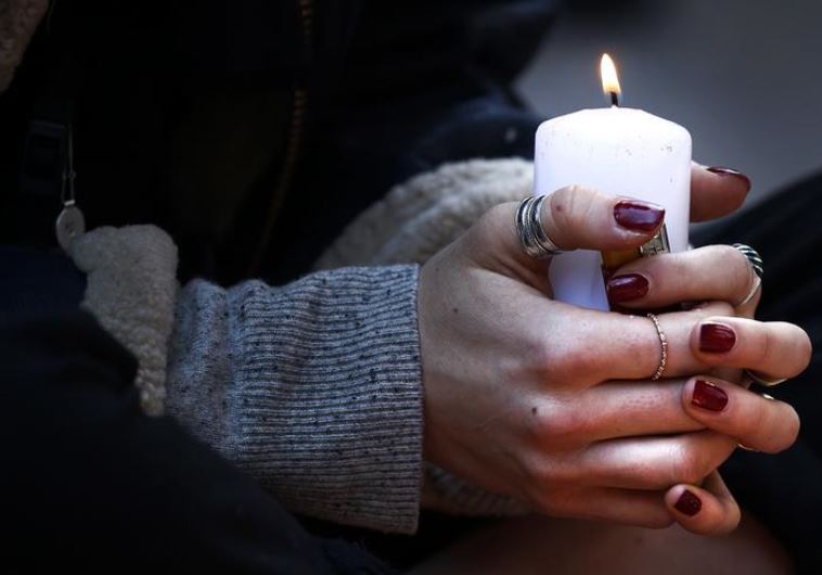 A woman holds a candle as she pays her respect at one of the attack sites in Paris, November 15, 2015. 