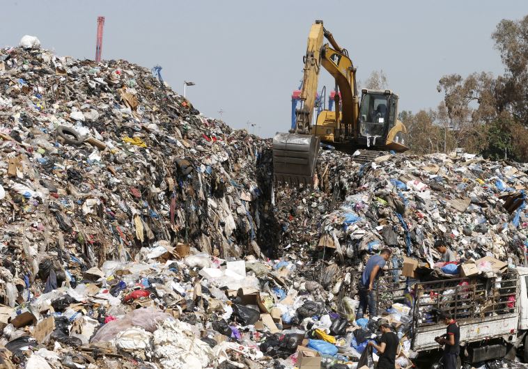 Men unload trash from a pick-up truck as scavengers sift through garbage at a temporary dump
