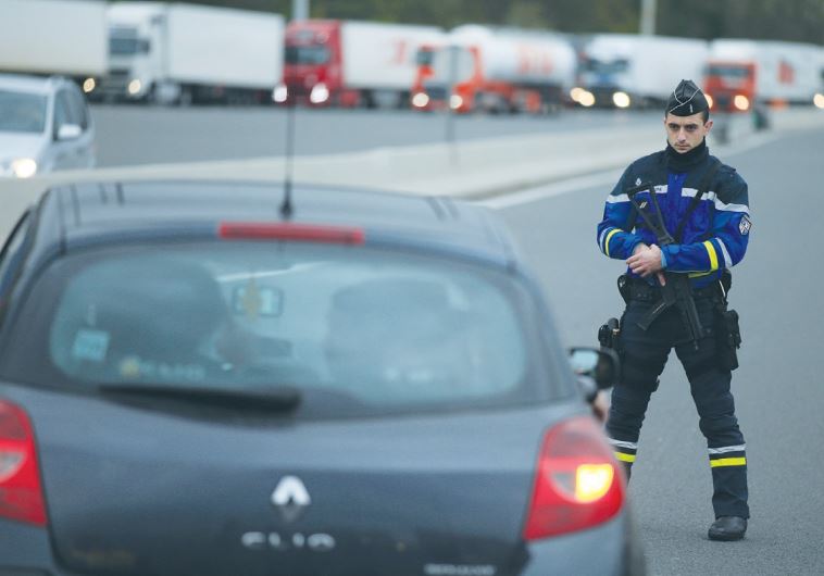 A FRENCH GENDARME stands along the road as he checks vehicles and verifies the identity of travelers on the A1 motorway