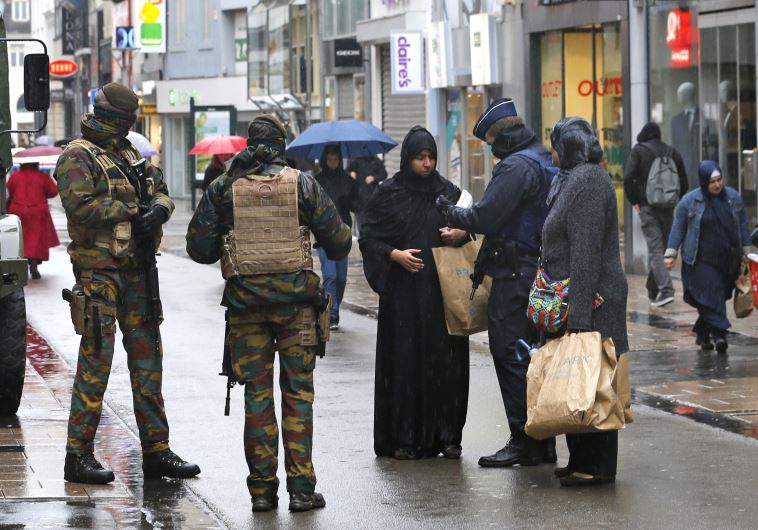 Belgian soldiers and a police officer control the documents of a woman in a shopping street in central Brussels, November 21, 2015