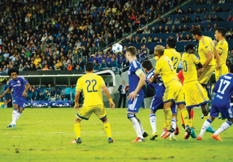 CHELSEA MIDFIELDER Willian (left) sends the ball soaring over the line on a free kick for the Blues’ second goal in their 4-0 Champions League victory over Maccabi Tel Aviv last night at Sammy Ofer Stadium in Haifa. 